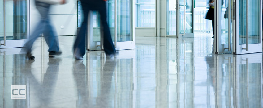 People walking on concrete flooring in a commercial building lobby