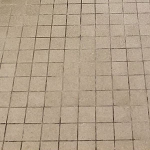 Restroom tile with dark, stained grout lines before restoration